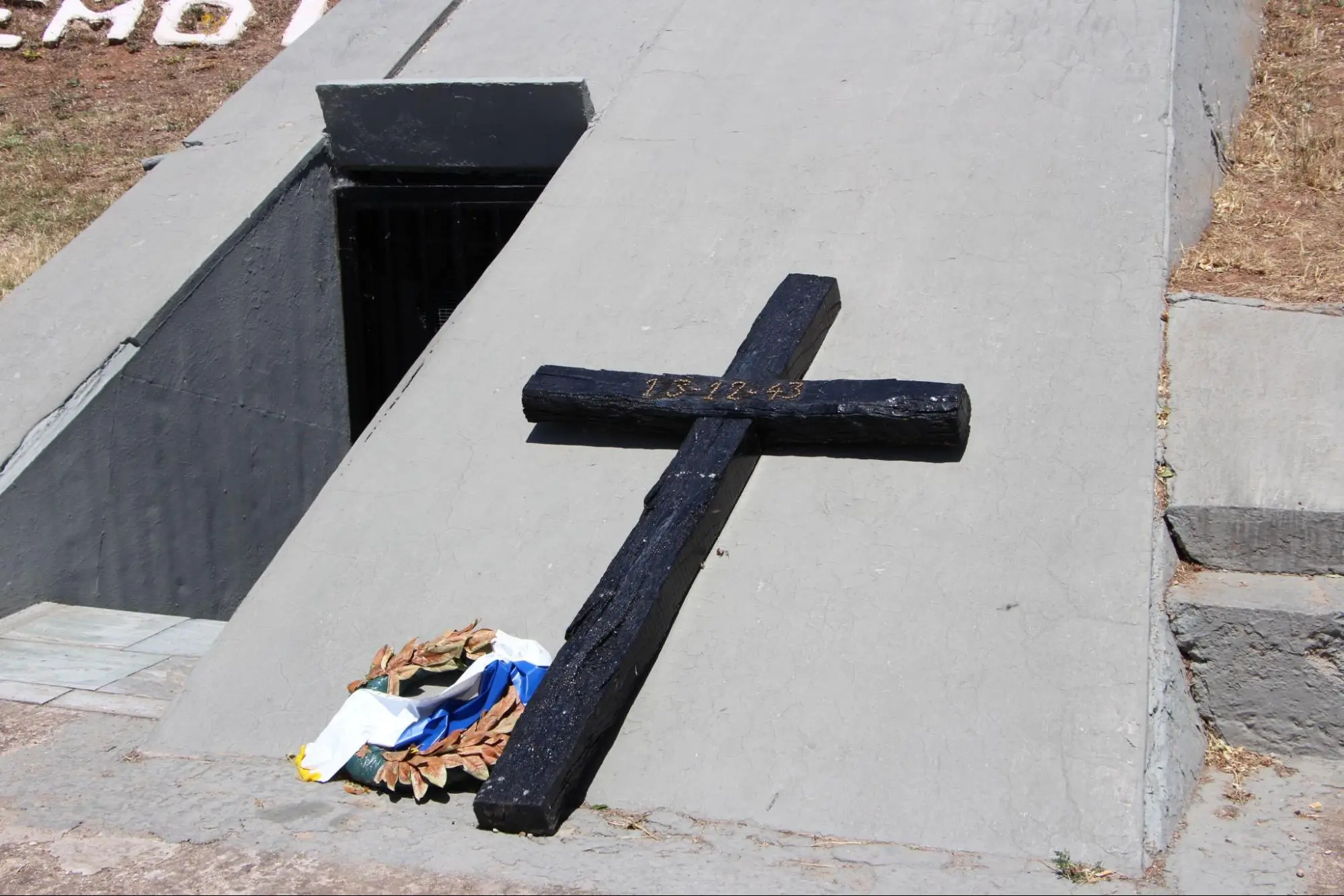 A cross rests against a WWII memorial in Kalavrita, Greece.